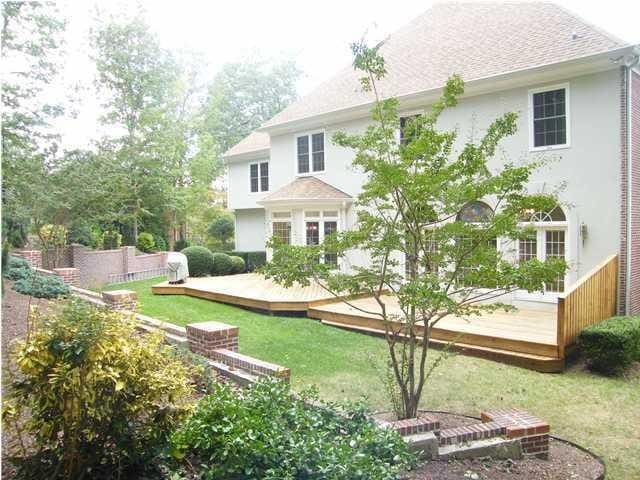 rear view of property featuring a wooden deck and a yard