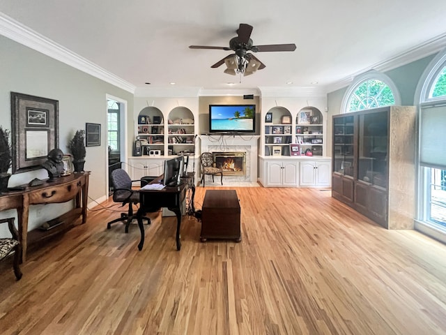 office featuring built in features, light hardwood / wood-style floors, ceiling fan, and a stone fireplace