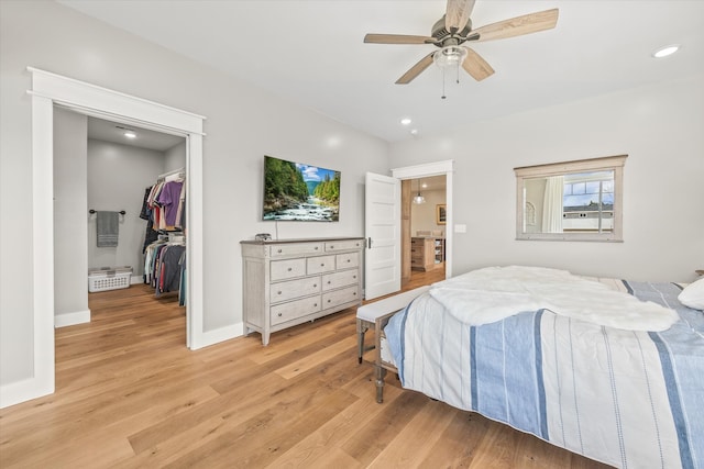 bedroom featuring a spacious closet, light wood-type flooring, a closet, and ceiling fan