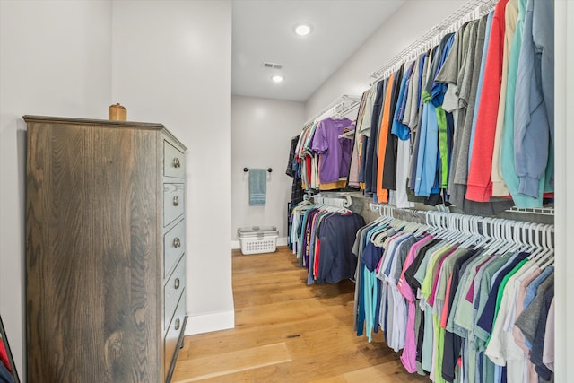 walk in closet with light hardwood / wood-style flooring