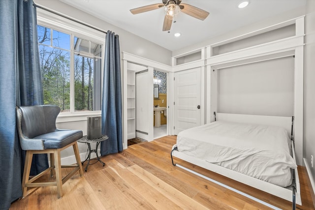 bedroom with hardwood / wood-style floors, ceiling fan, ensuite bathroom, and a closet