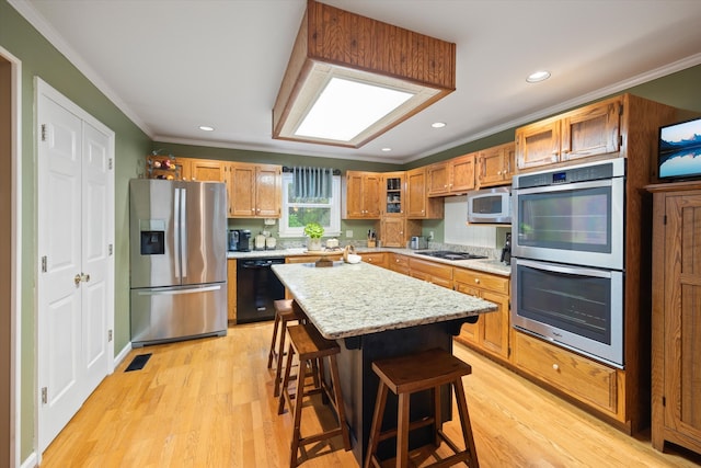 kitchen with appliances with stainless steel finishes, light hardwood / wood-style flooring, a center island, and a breakfast bar