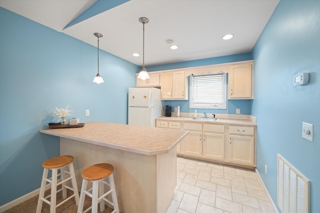 kitchen featuring a kitchen breakfast bar, decorative light fixtures, light tile flooring, white fridge, and sink