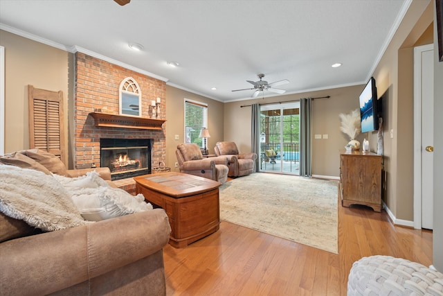 living room featuring ceiling fan, a fireplace, brick wall, ornamental molding, and light hardwood / wood-style flooring