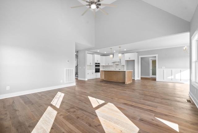 unfurnished living room featuring visible vents, baseboards, ceiling fan with notable chandelier, and light wood finished floors