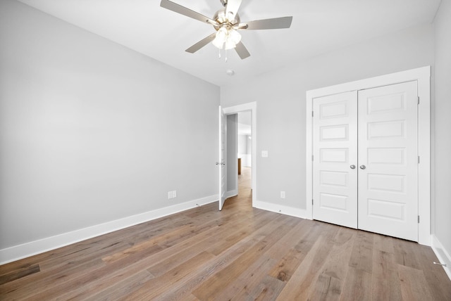 unfurnished bedroom with a closet, a ceiling fan, light wood-type flooring, and baseboards