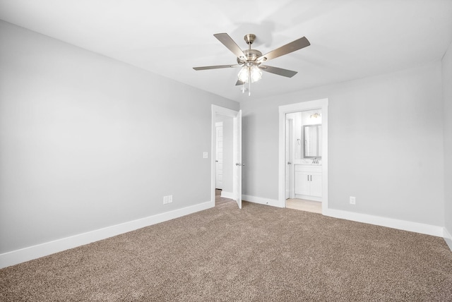 unfurnished bedroom featuring light colored carpet, baseboards, ensuite bathroom, and ceiling fan