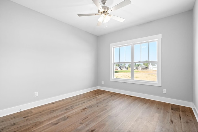 spare room with visible vents, baseboards, wood finished floors, and a ceiling fan