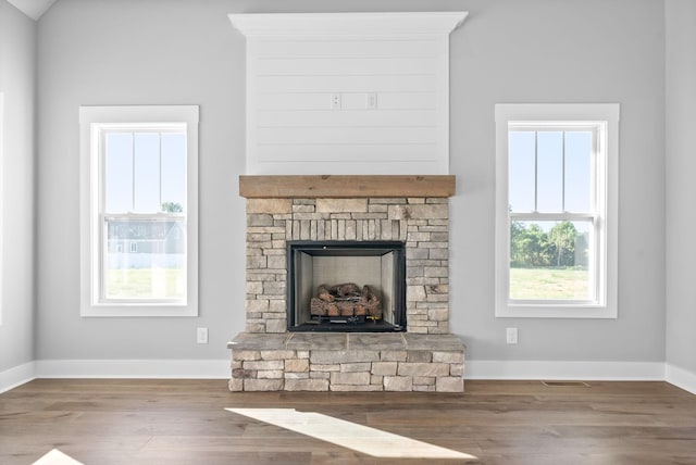 unfurnished living room featuring wood finished floors, a fireplace, baseboards, and visible vents