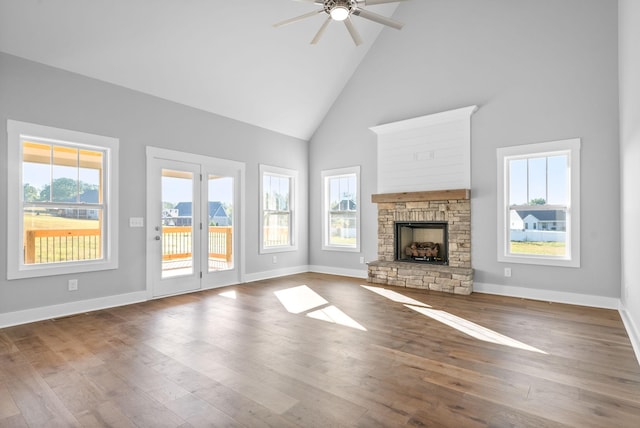 unfurnished living room with high vaulted ceiling, wood finished floors, a fireplace, baseboards, and ceiling fan