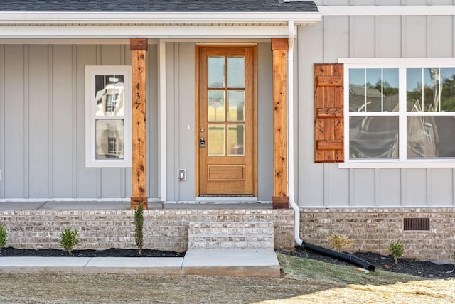 doorway to property featuring board and batten siding and roof with shingles