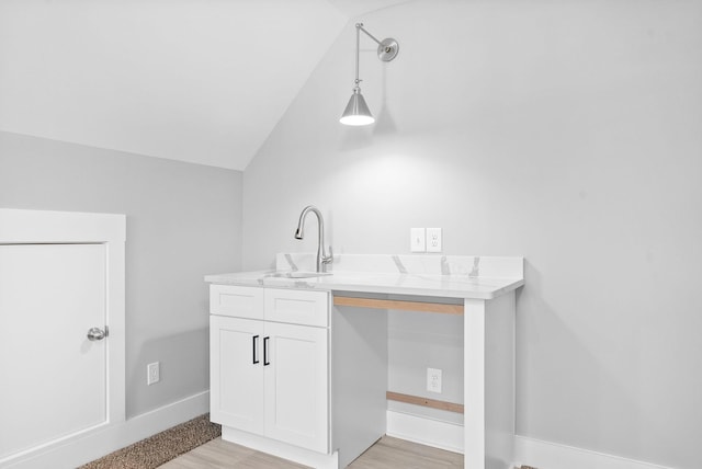 interior space with a sink, baseboards, lofted ceiling, and wood finished floors