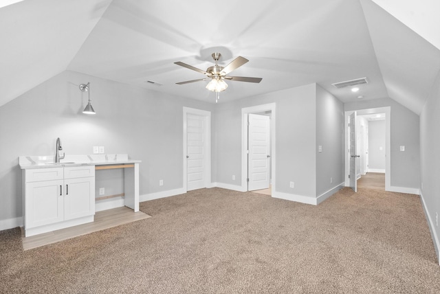 unfurnished living room with light carpet, visible vents, lofted ceiling, and a sink