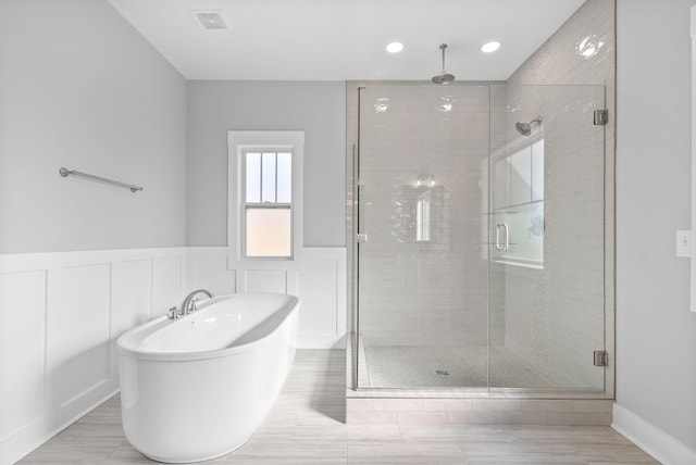 full bathroom with a freestanding bath, a stall shower, visible vents, and wainscoting