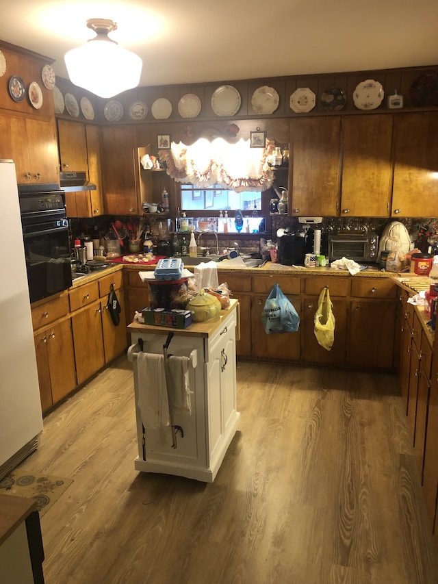 kitchen with backsplash, hardwood / wood-style floors, white refrigerator, and black oven