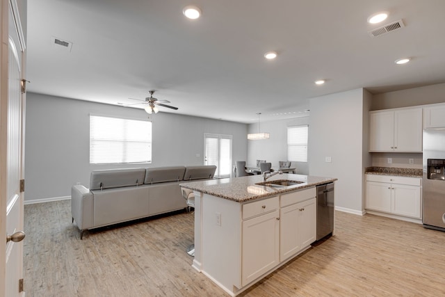 kitchen with light hardwood / wood-style floors, an island with sink, white cabinets, stainless steel appliances, and ceiling fan