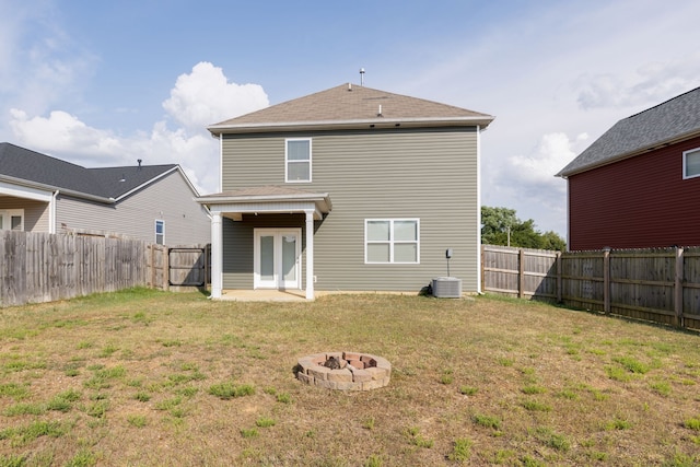 rear view of house featuring cooling unit, a fire pit, and a yard