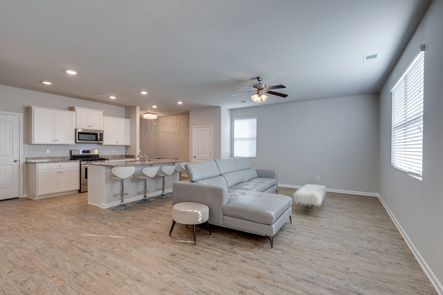 living room featuring ceiling fan, light wood-type flooring, and sink