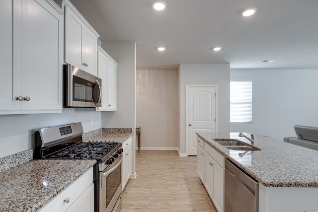 kitchen featuring light hardwood / wood-style floors, sink, white cabinetry, a center island with sink, and appliances with stainless steel finishes