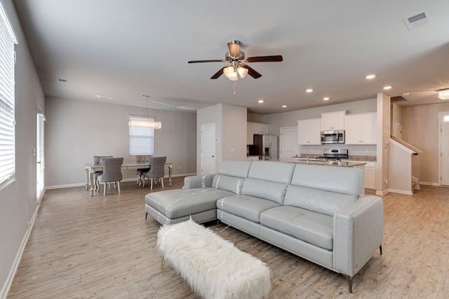 living room with ceiling fan and light hardwood / wood-style floors