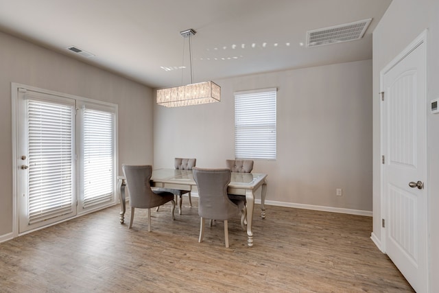 dining space with light hardwood / wood-style flooring and a notable chandelier