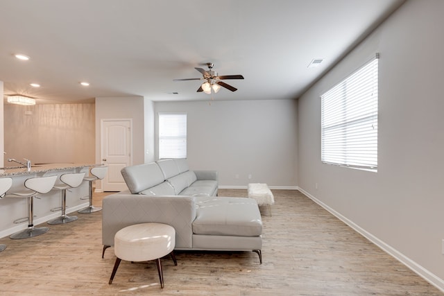 living room featuring ceiling fan, light wood-type flooring, and a healthy amount of sunlight