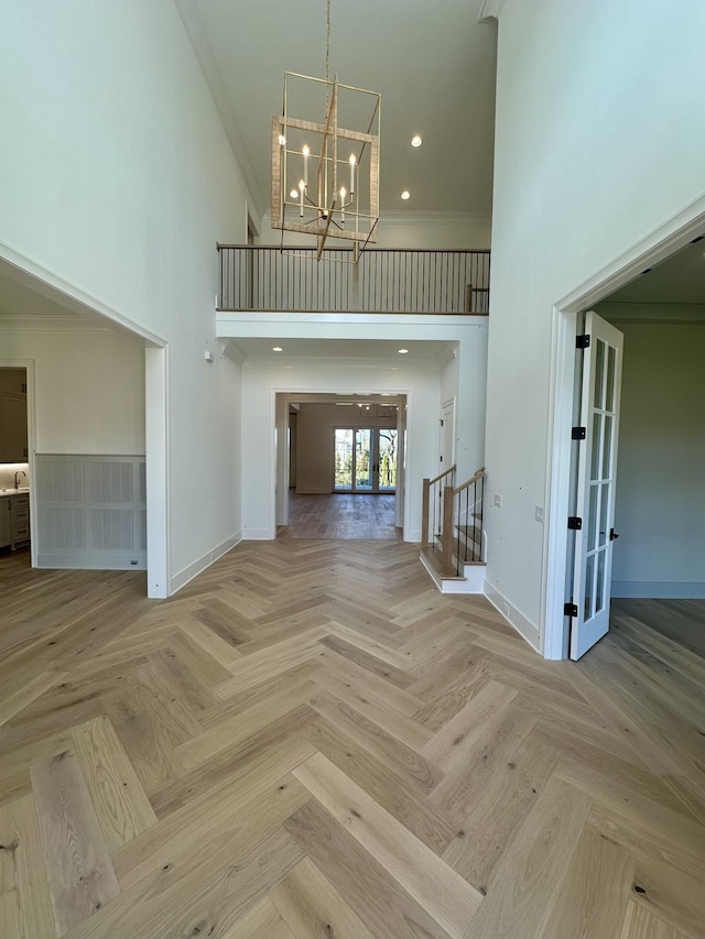 entrance foyer with light parquet flooring, a high ceiling, ornamental molding, french doors, and a chandelier