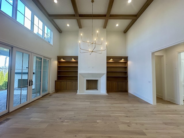 unfurnished living room with coffered ceiling, french doors, an inviting chandelier, and light wood-type flooring