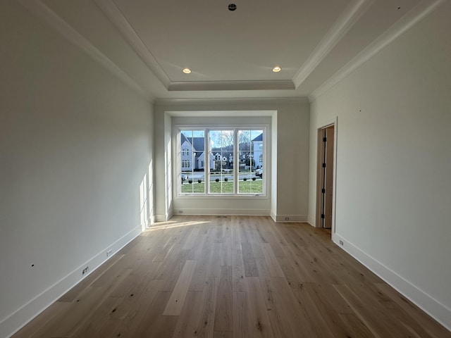 unfurnished room with light hardwood / wood-style flooring, ornamental molding, and a raised ceiling