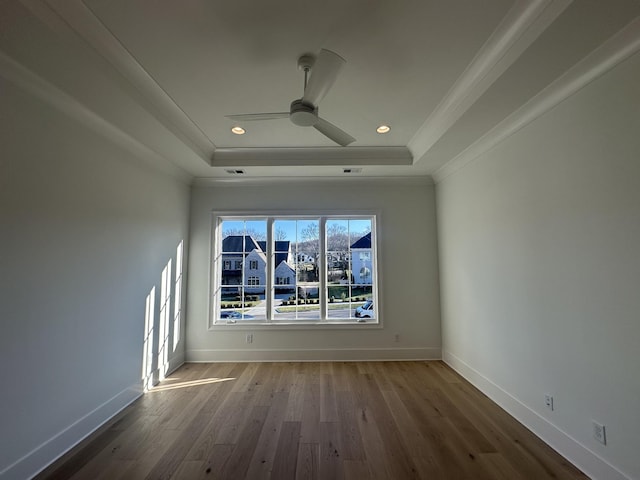 empty room with ceiling fan, ornamental molding, a raised ceiling, and hardwood / wood-style floors