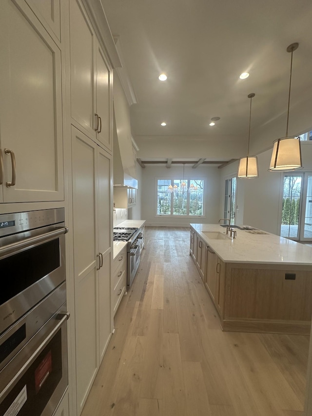 kitchen with light stone counters, hanging light fixtures, a large island with sink, custom range hood, and stainless steel appliances