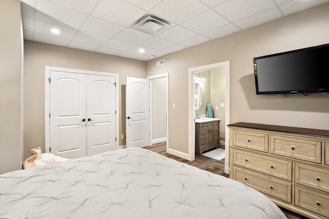 bedroom with a closet, dark wood-type flooring, a paneled ceiling, and ensuite bathroom