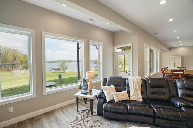 living room with light hardwood / wood-style flooring, a water view, and a wealth of natural light