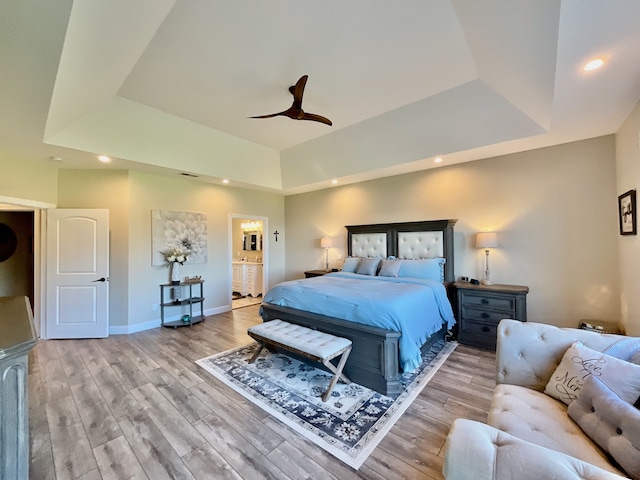 bedroom featuring light wood-type flooring, ceiling fan, and a tray ceiling