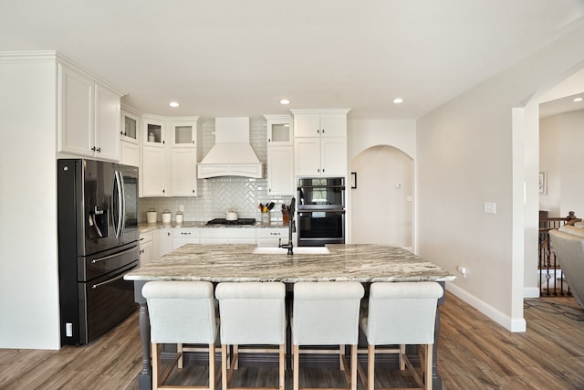 kitchen featuring backsplash, custom exhaust hood, stainless steel appliances, and white cabinetry