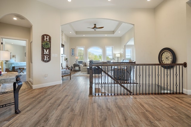 corridor featuring wood-type flooring and a raised ceiling