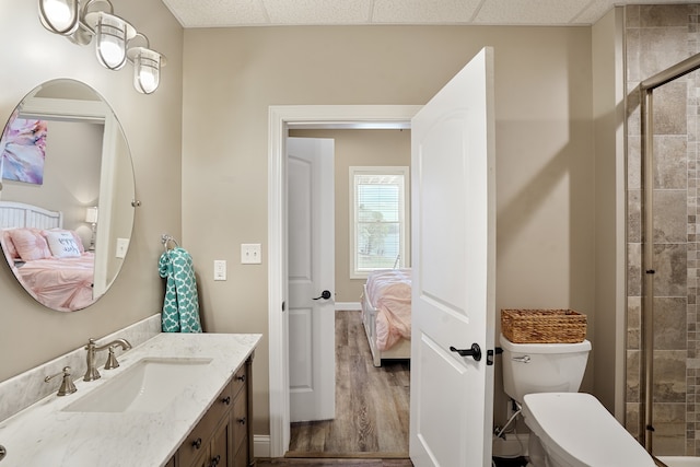 bathroom featuring a drop ceiling, toilet, vanity, and hardwood / wood-style flooring