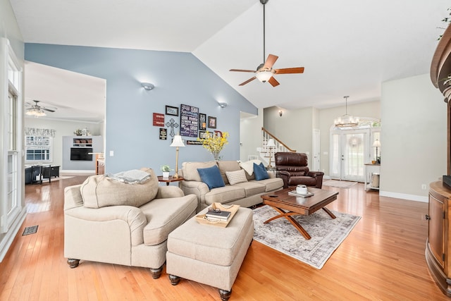 living room with ceiling fan with notable chandelier, plenty of natural light, and wood-type flooring