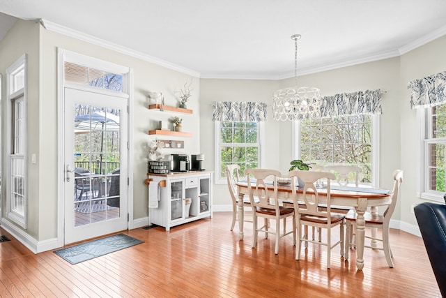 dining room with a wealth of natural light, light wood-type flooring, a chandelier, and ornamental molding