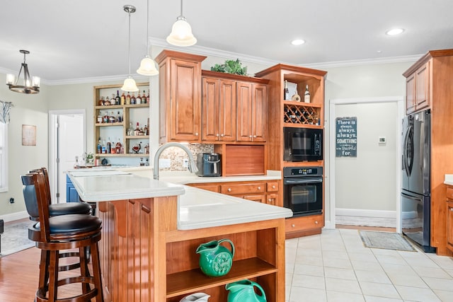 kitchen with crown molding, black appliances, light tile floors, a notable chandelier, and a breakfast bar area