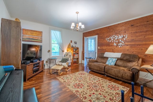 living room featuring wooden walls, ornamental molding, dark hardwood / wood-style floors, and a chandelier