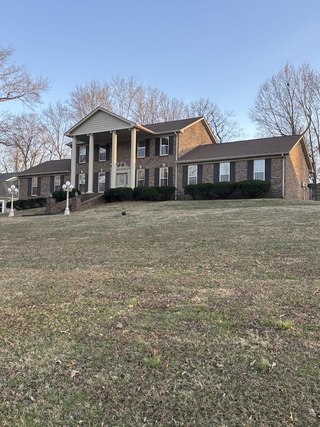 neoclassical home featuring brick siding and a front yard