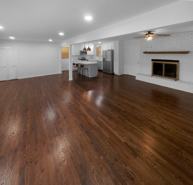 unfurnished living room with brick wall, dark hardwood / wood-style flooring, ceiling fan, and a fireplace