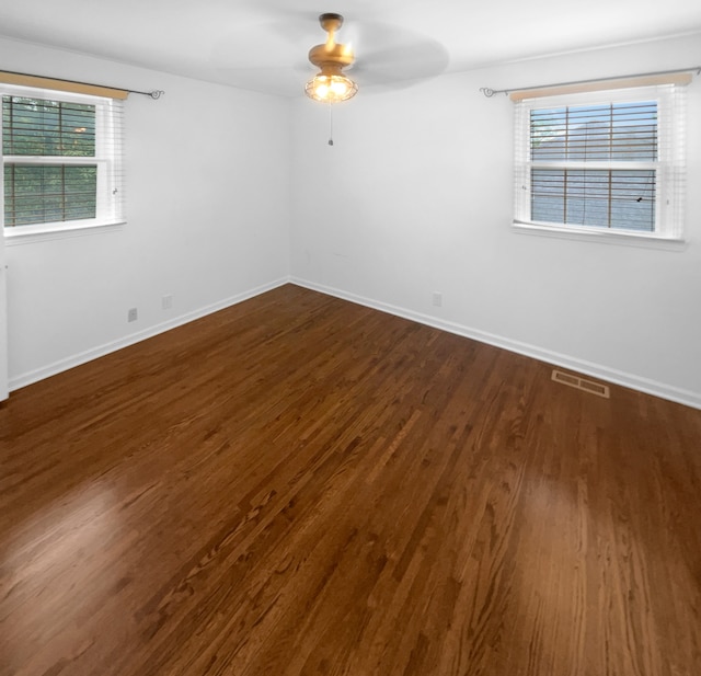 unfurnished room with a healthy amount of sunlight, ceiling fan, and dark hardwood / wood-style floors