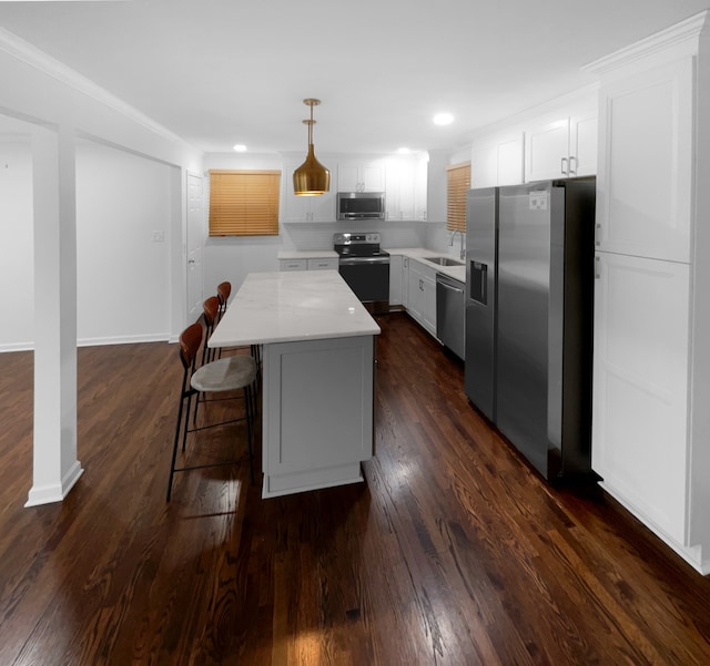 kitchen featuring a kitchen island, white cabinetry, stainless steel appliances, dark hardwood / wood-style floors, and pendant lighting