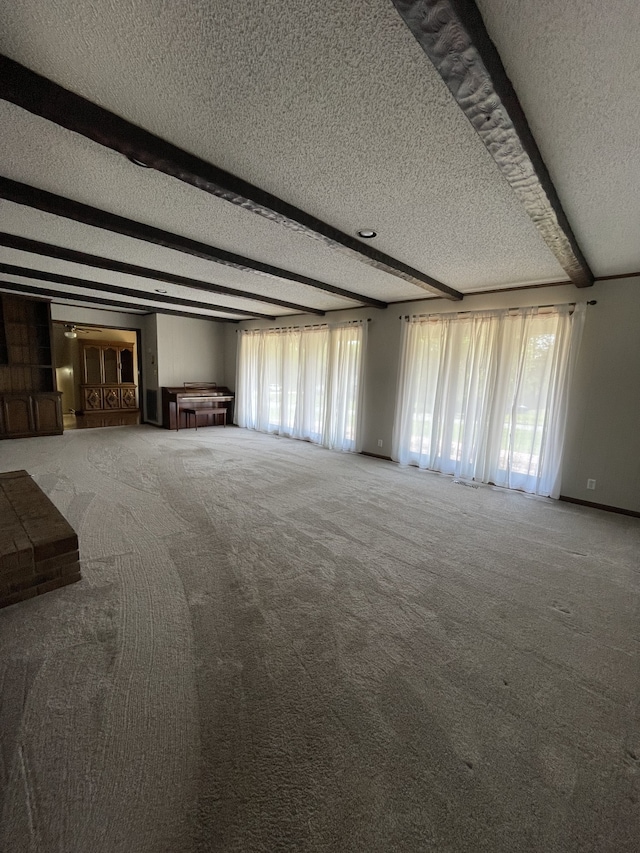 unfurnished living room featuring carpet floors, beamed ceiling, and a textured ceiling