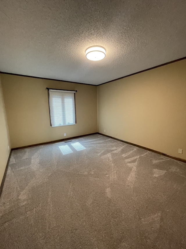 carpeted empty room with ornamental molding and a textured ceiling