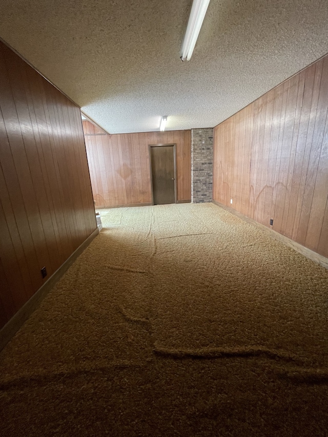 basement with carpet, a textured ceiling, and wooden walls