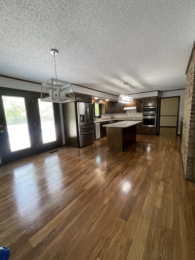 kitchen featuring dark brown cabinetry, stainless steel fridge, white dishwasher, pendant lighting, and a kitchen island