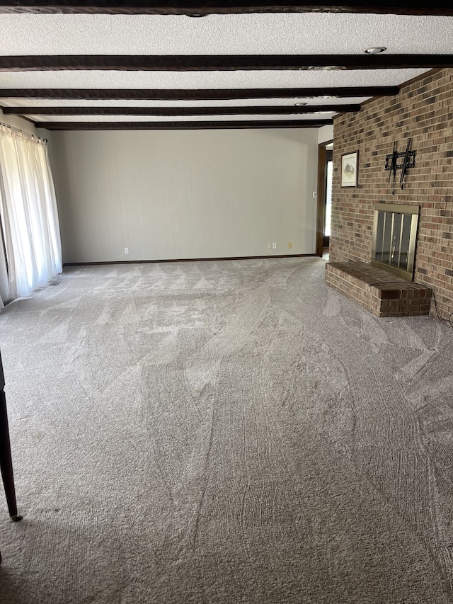 unfurnished living room featuring beamed ceiling, light carpet, and a brick fireplace